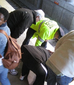 JFK-UMass rescue: An MBTA police officer and commuters tend to a woman moments after she was pulled from the tracks at JFK-UMass. Photo by Ed Forry