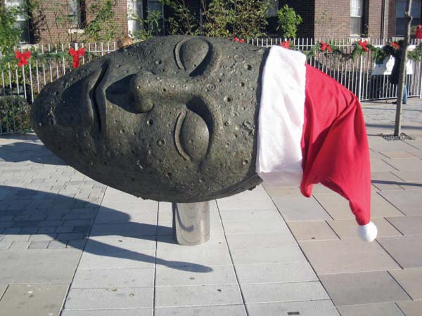 Sleeping Moon: Someone had the holiday notion recently to affix a Santa’s helper’s cap on The Sleeping Moon public art exhibit at Ashmont Station. No doubt it’s a pose that many human helpers of old St. Nick are hoping to strike once this week’s push to Christmas is over. 	Photo by Judy Tuttle