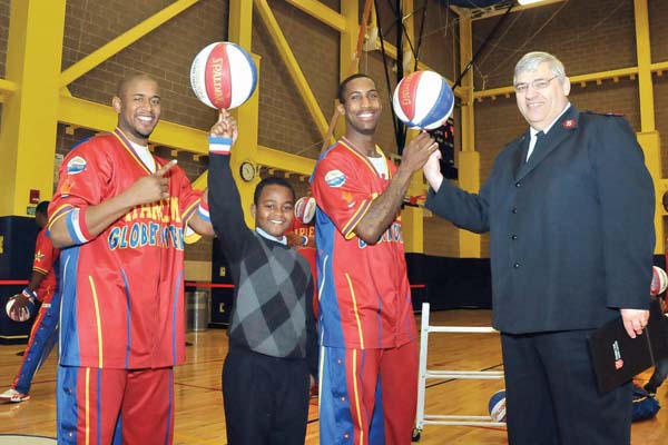 Globetrotters Visit Brand New Kroc Center : Players from the Harlem Globetrotters dropped by the Salvation Army’s recently opened Kroc Center on Dudley Street on Monday to sharpen their skills in front of students from Dorchester’s Ralph Waldo Emerson Elementary School. The Globetrotters are in town for two games at the TD Garden this weekend.  It was the first official event at The Kroc Center, kicking off a series of launch celebrations that will culminate in an April 2 ribbon-cutting. Above, from left, Scooter Christensen, Erickson Gomes, age 11, Bull Bulliard, and Major William Bode, Divisional Commander of Massachusetts Salvation Army. Related photo, Page 19. 	Photo by Steve Babineau.