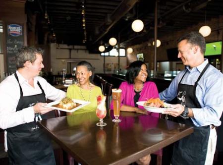 In preparation for next Thursday’s event, Ben Johnson, Blarney Stone, and Jonathan Elias, Anchor TV38, serve up food to Millie Clements, Men of Boston Host Committee Member, and Sandra Cotterell, CEO Codman Square Health Center. 	Scotland Huber photo 