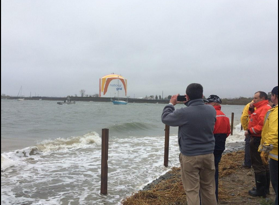 Members of the Savin Hill Yacht Club and UMass Boston watch as another beached boat is towed to safety. Photo by Lauren Dezenski