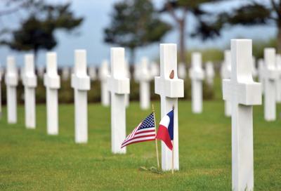 An American flag and a French flag offer tribute to a fallen US soldier at the American Cemetery at Colleville-sur-Mer, Normandy, where 9,387 American war dead  are at rest. 	Stars and Stripes photo by Michael Abrams