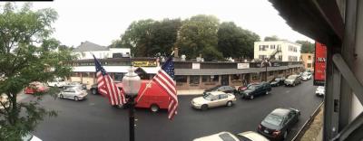 A block of stores along Adams Street, shown to the right of the flags, have recently been acquired by new owners— John and Peter Lydon, who plan to make improvements to the storefronts. 	Bill Forry photo