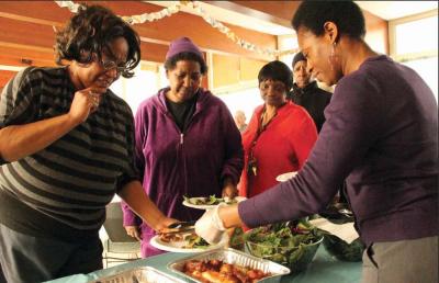 Catherine Louis, right, served meals to volunteers who help organize Rosie’s Place outreach efforts in the Franklin Field Housing Development. Caleb Nelson photo