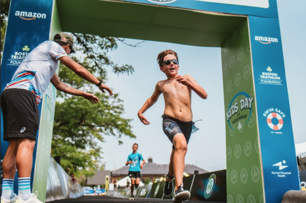 A boy runs across the finish line of the Boston triathlon